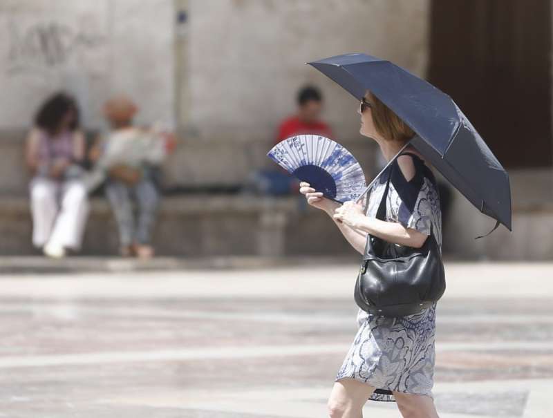 Una mujer se abanica y se protege del sol con un paraguas. EFE/Kai Försterling/Archivo
